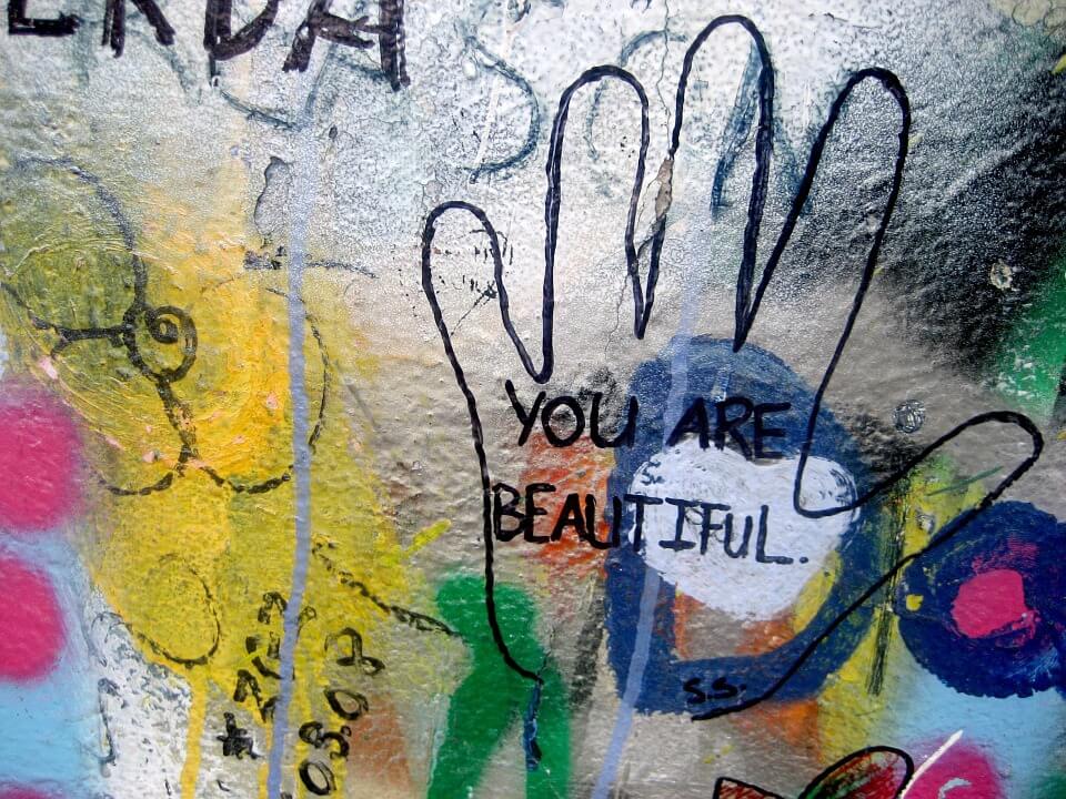 Muurschildering Van Bloemen En Een Hand Waar You Are Beautiful In Staat Geschreven