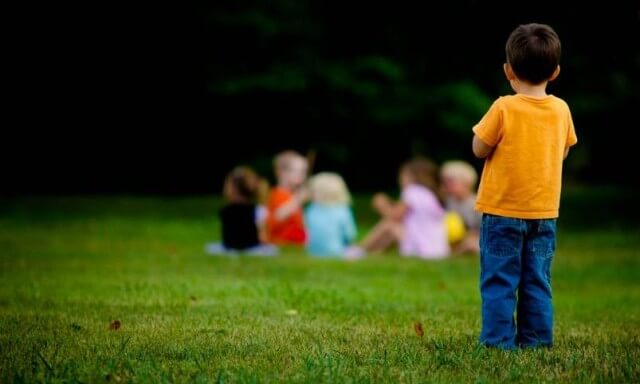 Jongetje Dat Alleen Staat Te Kijken Naar Een Groep Kinderen Verderop Als Voorbeeld Van Hoe Kinderen Die Lijden Aan Het Syndroom Van Asperger Zijn