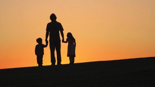 Een vader die met zijn twee kinderen wandelt