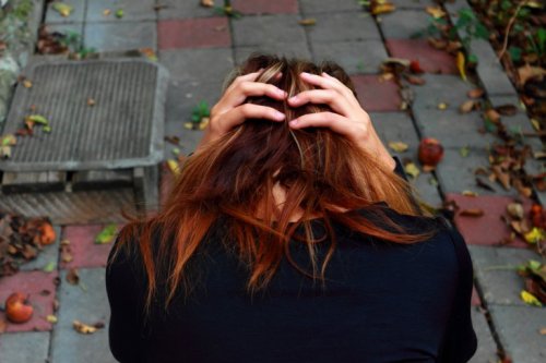 Meisje dat in de tuin zit met haar hoofd voorover gebogen omdat ze last heeft van obsessieve-compulsieve stoornis