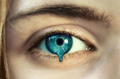 Blauwe oog van een meisje waar een blauwe druppel uitvalt
