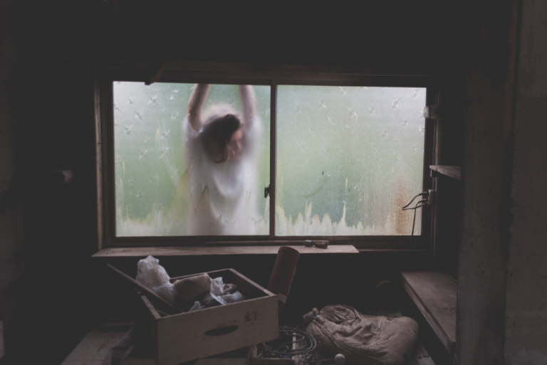 Vrouw die tegen een raam aan hangt omdat ze last heeft van dysthymie