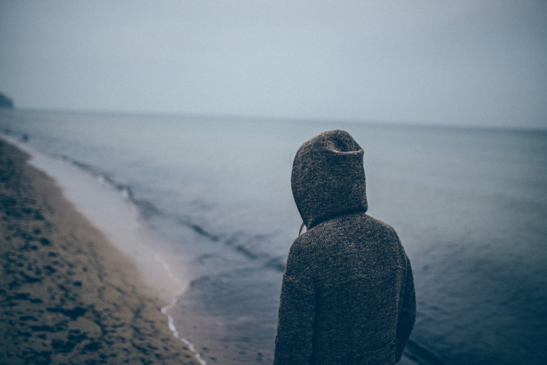 Jongen die alleen over het strand loopt, maar heeft hij last van depressie of dysthymie