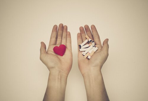 Twee handen waarvan er in een een hartje ligt en in de andere gebroken sigaretten als hulp bij stoppen met roken