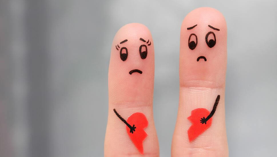 Twee verdrietige vingers die ieder een deel van een gebroken hart vasthouden vanwege een breuk in hun relatie