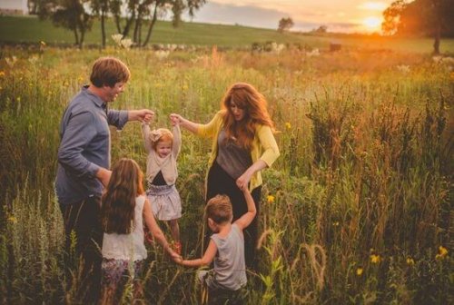 Een gezin dat vrolijk speelt in een weiland bij zonsondergang 
