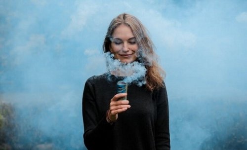 Vrouw die een rookbom voor haar gezicht houdt maar nog steeds staat te lachen