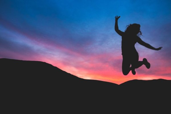 Vrouw die bij zonsondergang een sprong in de lucht maakt vanwege haar persoonlijk empowerment