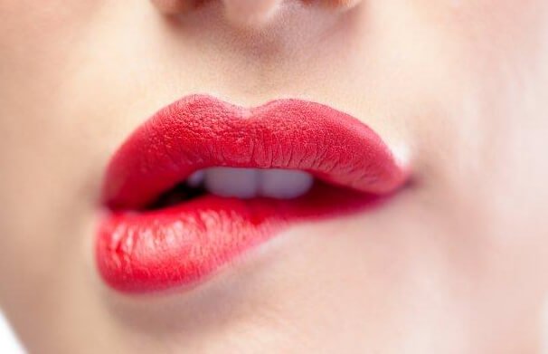 Vrouw met rode lippenstift op die op haar lip bijt en dit kan wantrouwen oproepen