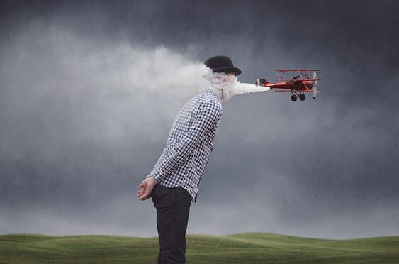 Man met vliegtuigje dat rook in zijn gezicht blaast