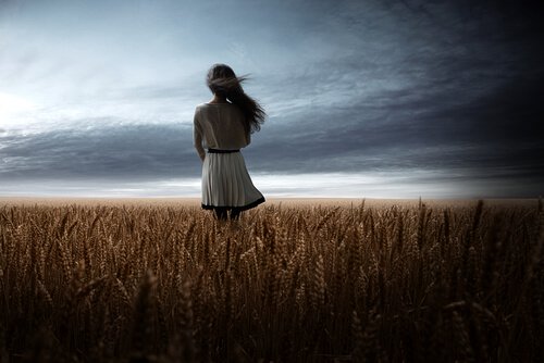 Meisje dat in een granenveld naar de donkere wolken staat te kijken