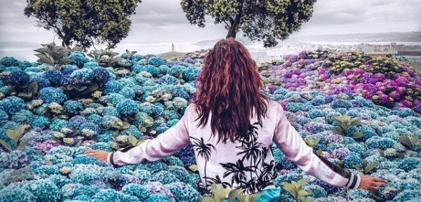 Vrouw tussen de blauwe en paarse bloemen