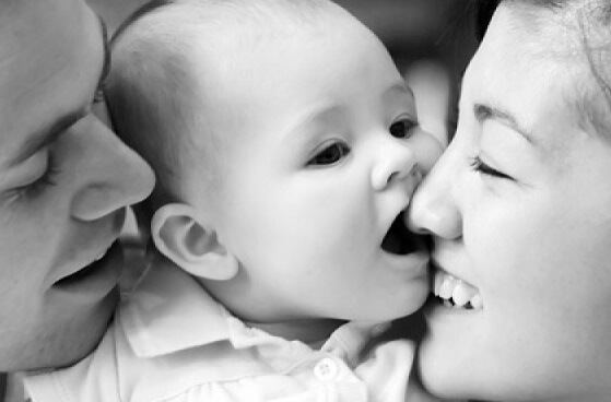 Twee ouders die hun gezicht tegen het gezicht van hun pasgeboren baby aan drukken en duidelijk geen vermijdende hechtingsstijl hebben