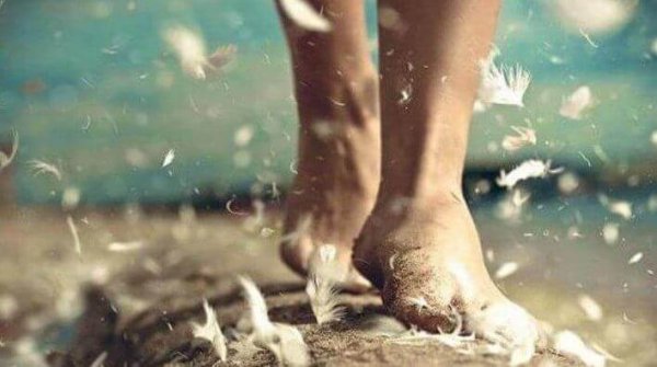 Vrouw die op blote voeten over veren loopt en geniet van mindfulness in het dagelijks leven