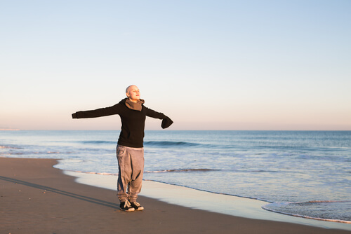 Vrouw met kanker die op het strand geniet van de frisse lucht