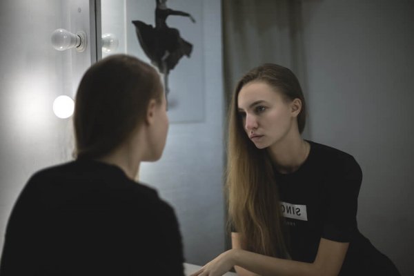 Meisje dat ontevreden naar zichzelf kijkt in de spiegel