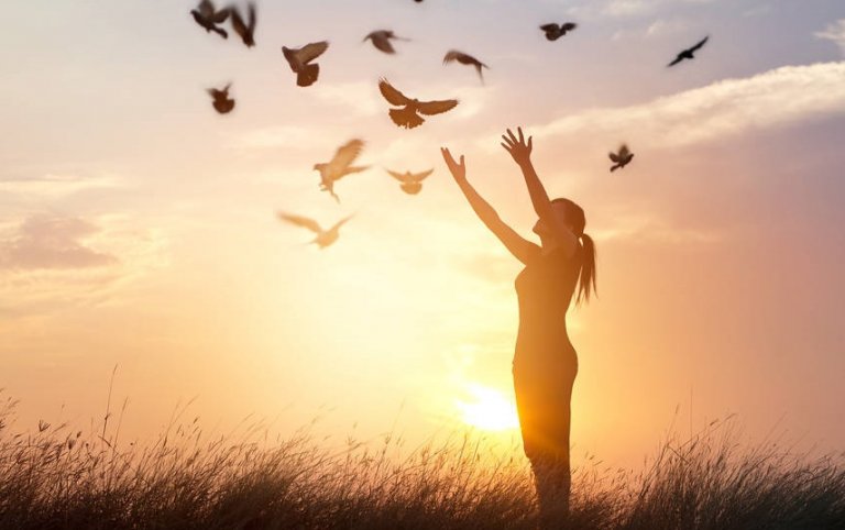 Vrouw die vogels vrijlaat bij zonsondergang