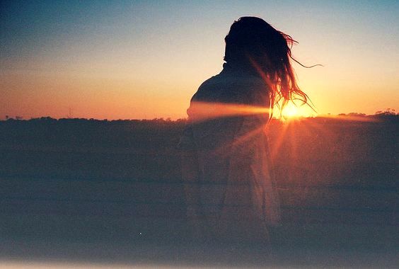 Vrouw die naar de ondergaande zon kijkt