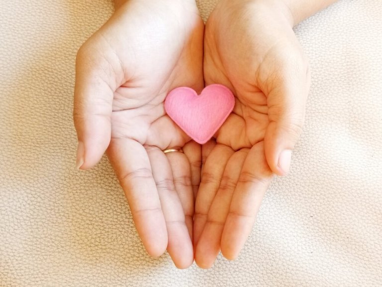 Een klein roze hartje in de handen van een vrouw