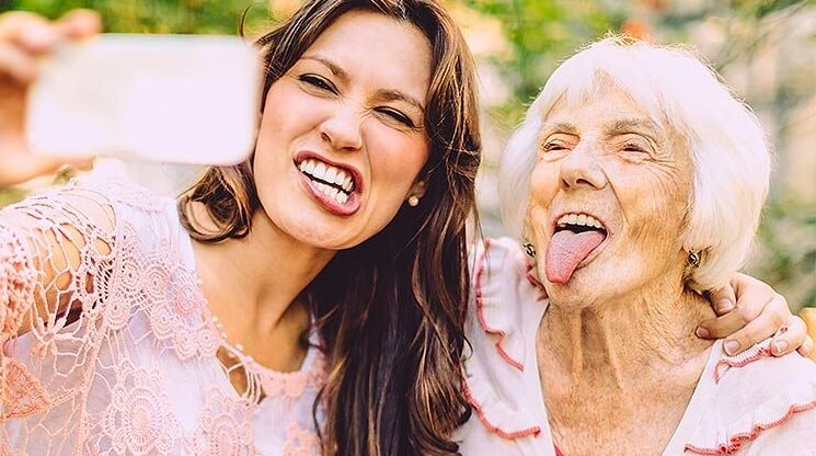 Een oudere vrouw die samen met een jongere vrouw een gekke bek trekt