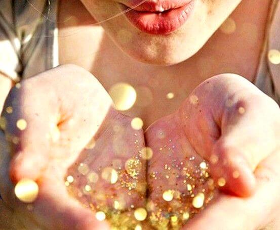 Vrouw die goud glitter uit haar handen blaast