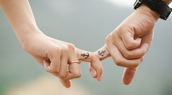 Handen met tattoos van ankers die elkaar wanhopig vasthouden, als symbool voor de afhankelijke persoonlijkheidsstoornis