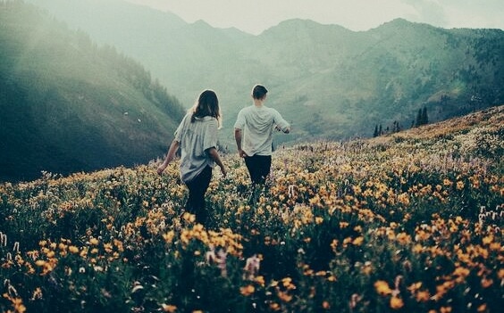 Jongen en een meisje die samen door een vallei lopen die vol bloemen staan
