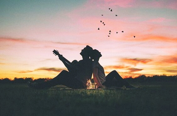 Twee mensen op een grasveld bij zonsondergang
