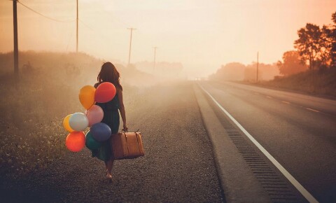 Vrouw met ballonnen en een koffer