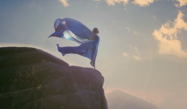 Vrouw die op een hoge rots staat met haar armen wijdgespreid
