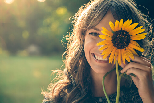 Vrouw die een zonnebloem voor haar oog houdt