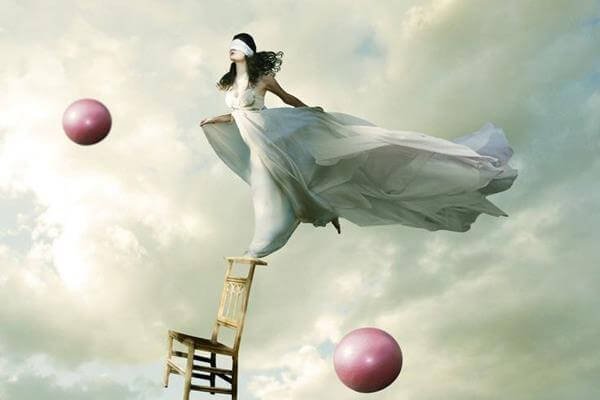 Vrouw die geblinddoekt balanceert op de leuning van een stoel