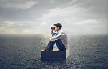 Man die op een steen midden in de oceaan door een verrekijker kijkt, want we moeten dingen doen die onmogelijk lijken
