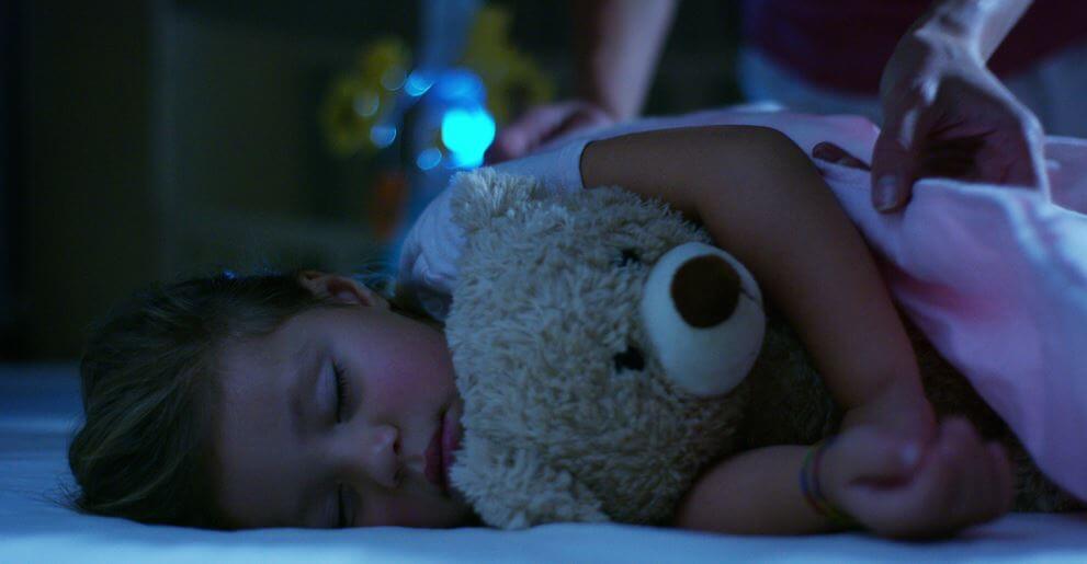 Meisje dat ligt te dromen met haar teddybeer in haar armen
