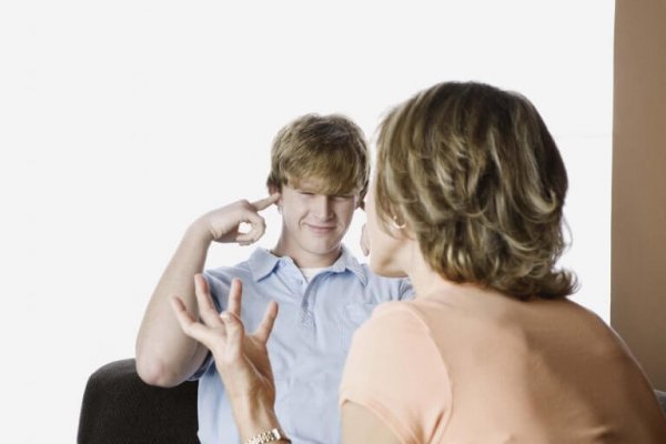 Jongen die zijn oren dichthoudt terwijl zijn moeder tegen hem praat, als voorbeeld van opstandige tieners