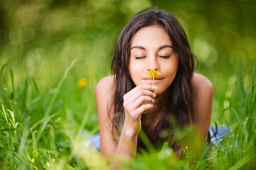 Vrouw ruikt aan bloem en weet: leven in het heden is belangrijk