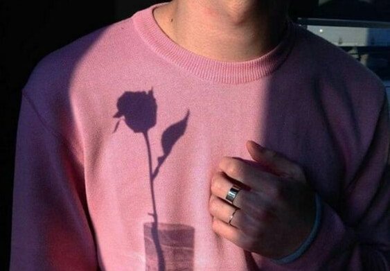 Man met een roze shirt waar de schaduw van een roos op te zien is
