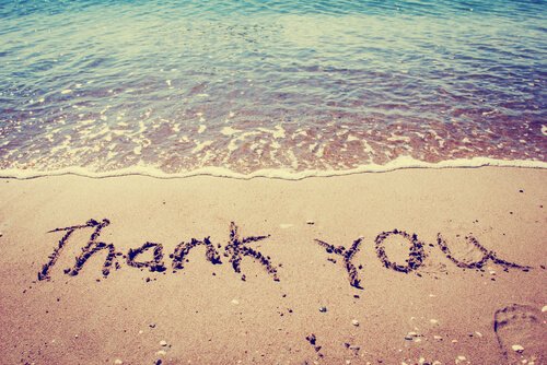 De woorden 'thank you' geschreven in het zand
