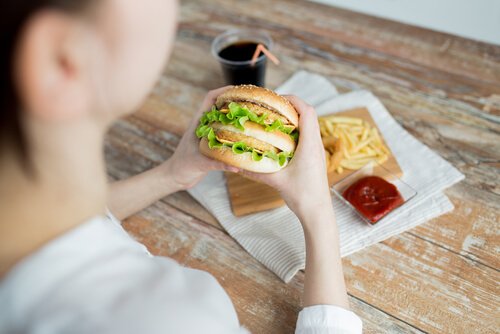 Vrouw met emotionele honger eet fastfood