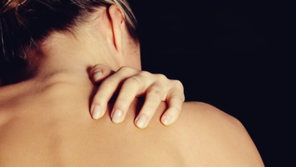 Huid en emoties: naakte vrouw raakt haar rug aan