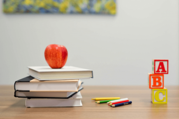 Stapel boeken met een appel erop, om leren voor kinderen met leerproblemen leuker te maken