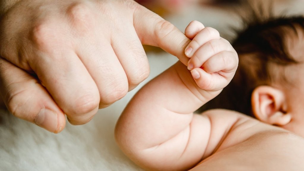 Baby die de hand van zijn vader vasthoudt, die co-ouderschap heeft