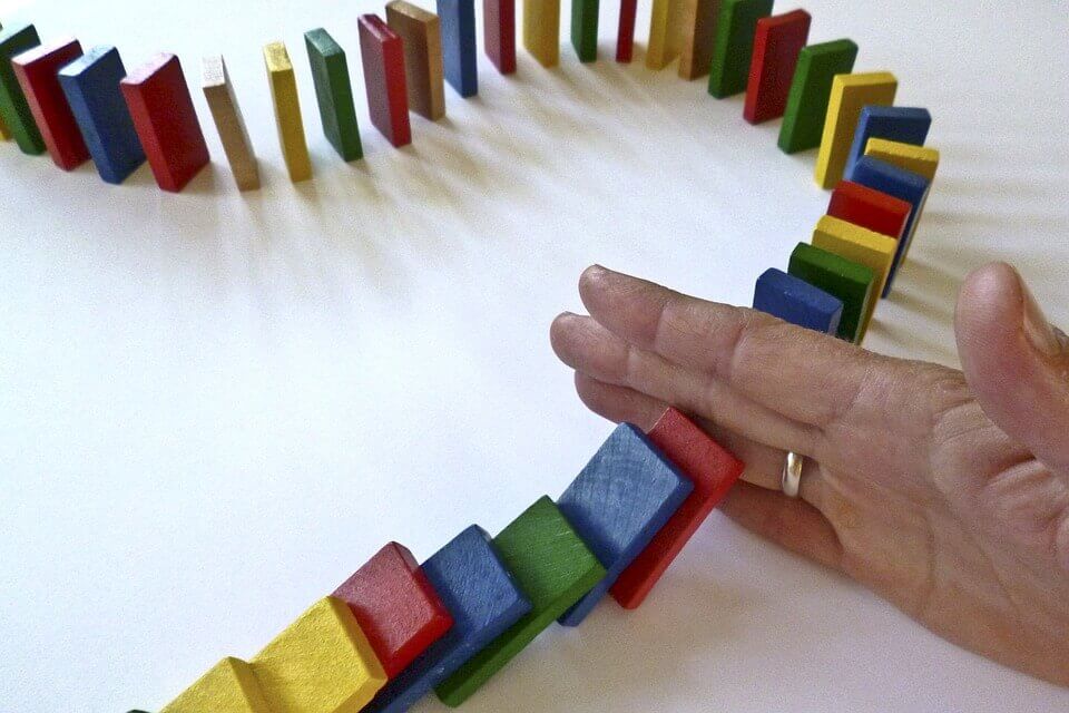 Hand die een paar domino's tegenhoudt, als voorbeeld van sociale macht