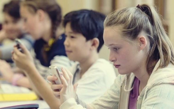 Scholieren zitten op hun telefoons in de klas: smartphone-generatie