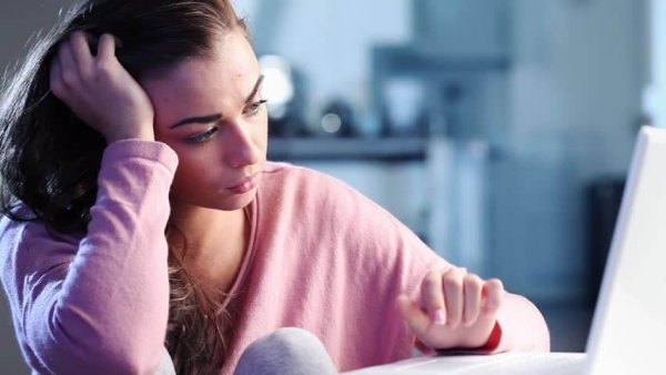 Verdrietig meisje leest iets op haar laptop