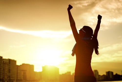 Vrouw strekt haar armen bij zonsopgang