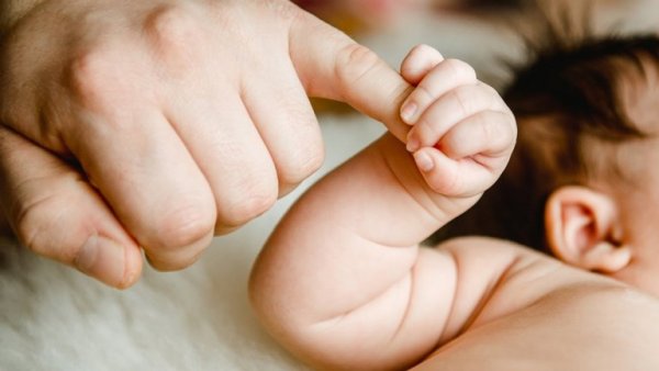 Baby grijpt vinger van moeder vast