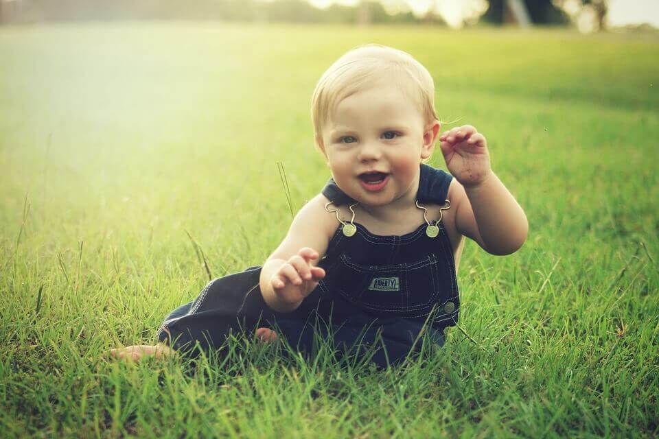 Kleine jongen in het gras, want baby's leren van alles op jonge leeftijd
