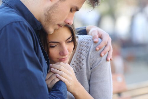 Jongen die zijn vriendin omhelst, want zij voelt meer pijn