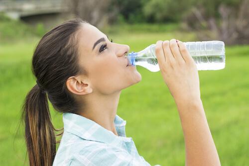 Vrouw die uit een flesje water drinkt